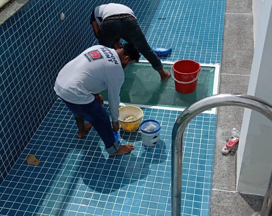 two workers applying a waterproofing treatment to a swimming pool