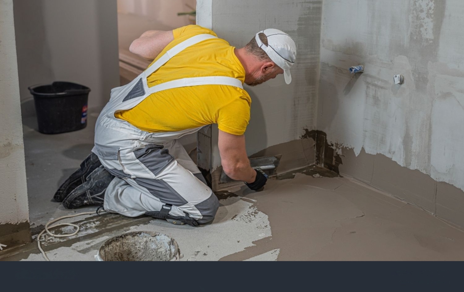 a worker applying a waterproofing liquid membrane to a bathroom floor and wall junction.